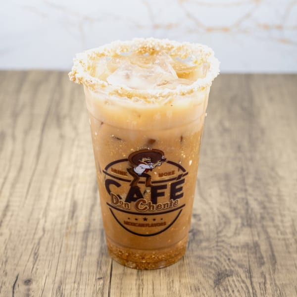 Iced horchata with a crushed cookie rim and Cafe Don Chente logo on a wooden table.