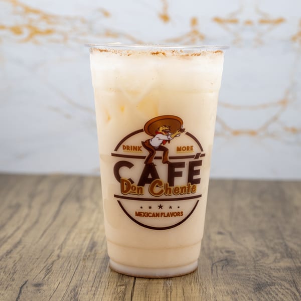 A Cafe Don Chente horchata drink with cinnamon on top, on a wooden table.